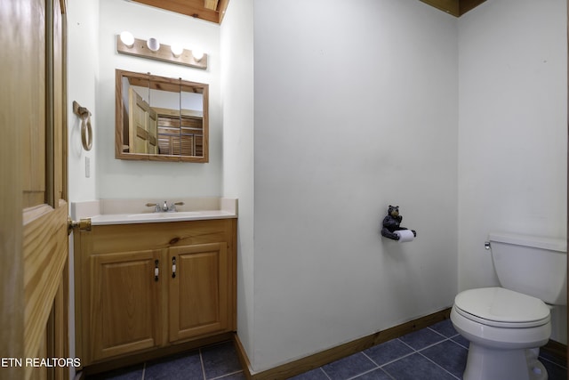 half bathroom with tile patterned floors, baseboards, toilet, and vanity