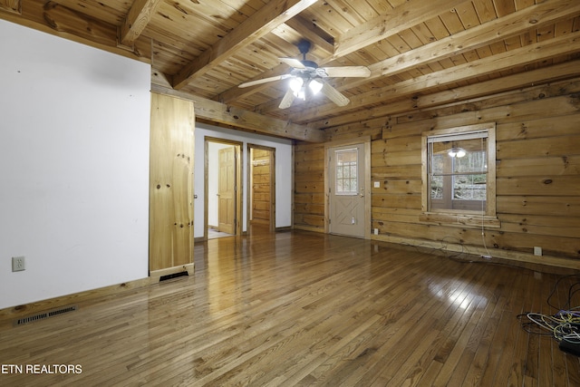 spare room featuring a ceiling fan, visible vents, hardwood / wood-style flooring, wooden ceiling, and beamed ceiling