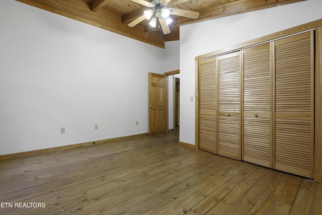 unfurnished bedroom with light wood finished floors, baseboards, wood ceiling, beam ceiling, and a closet