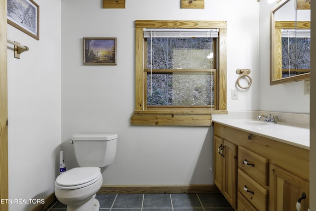 half bathroom featuring tile patterned flooring, toilet, vanity, and baseboards