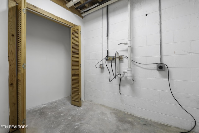 bathroom featuring concrete block wall and unfinished concrete flooring