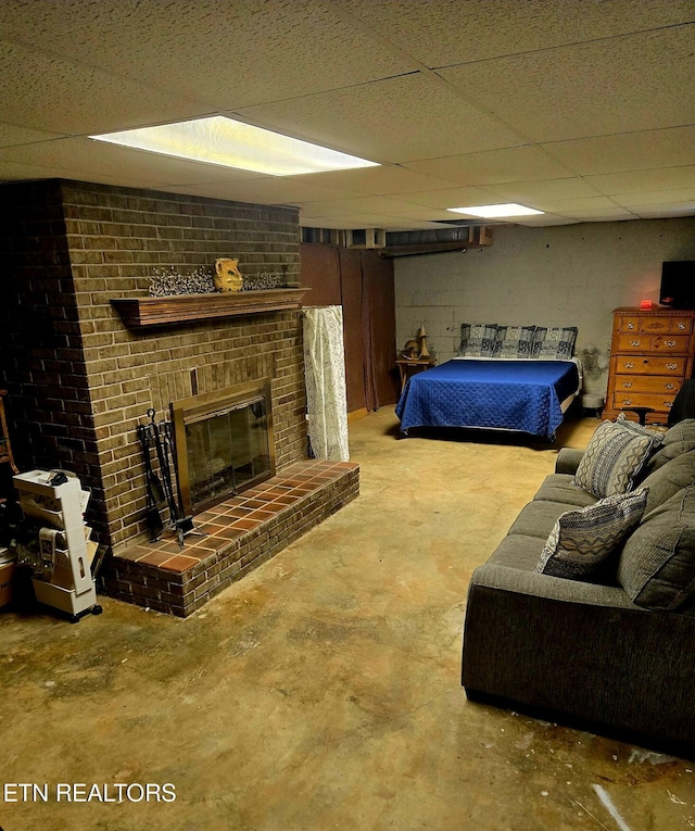 bedroom featuring a paneled ceiling, concrete flooring, a brick fireplace, and concrete block wall