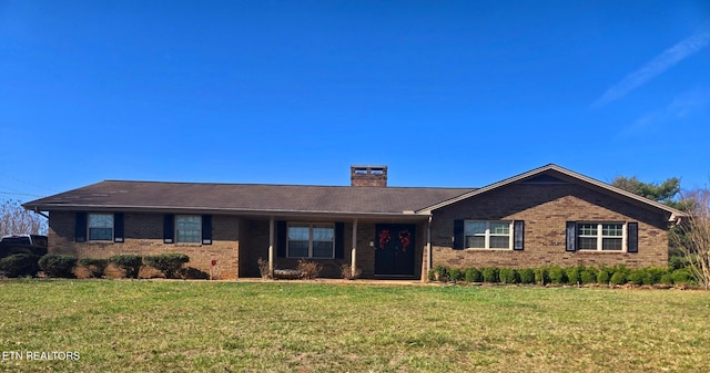 ranch-style house with a front yard, brick siding, and a chimney