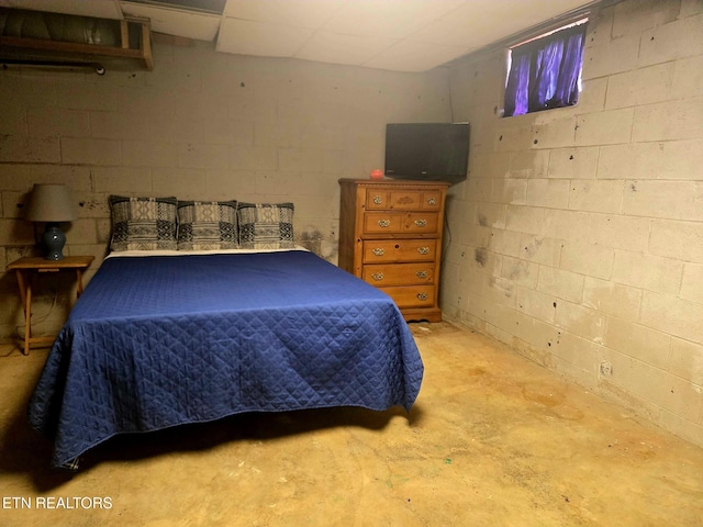 bedroom with unfinished concrete flooring and concrete block wall