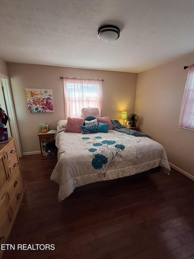 bedroom featuring a textured ceiling, baseboards, and wood finished floors