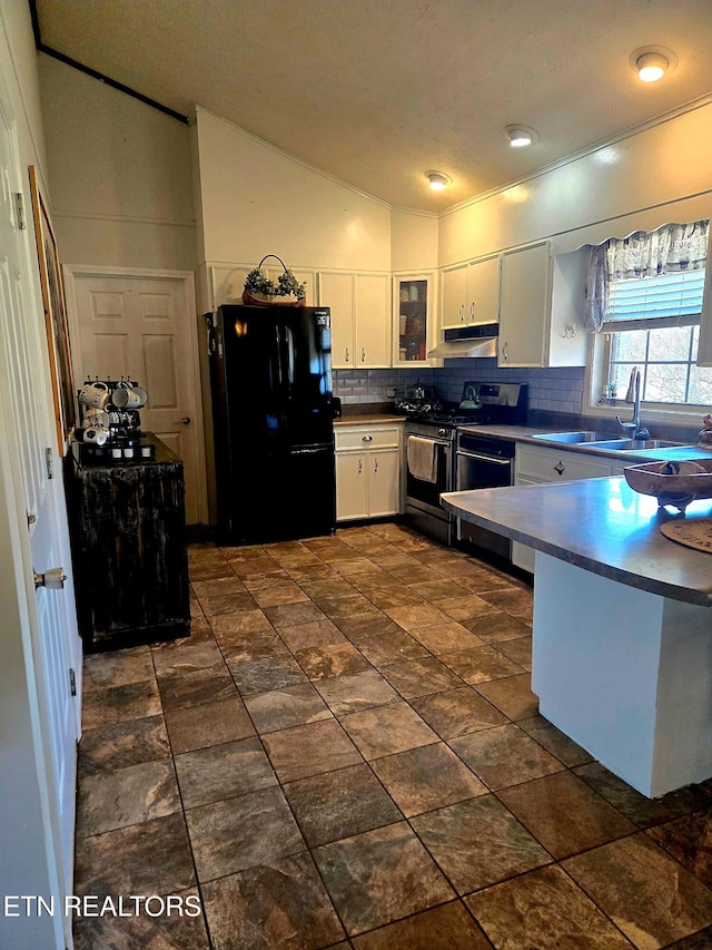 kitchen featuring lofted ceiling, freestanding refrigerator, a sink, under cabinet range hood, and range with gas cooktop