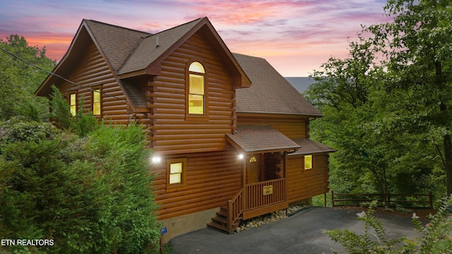 view of front of property with log exterior, fence, and roof with shingles