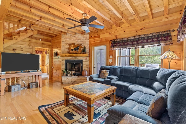 living area featuring beam ceiling, a ceiling fan, wood finished floors, wooden walls, and wooden ceiling