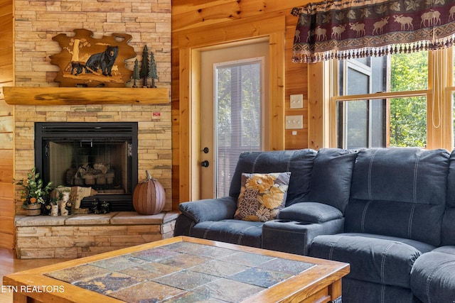 living room with wooden walls and a stone fireplace