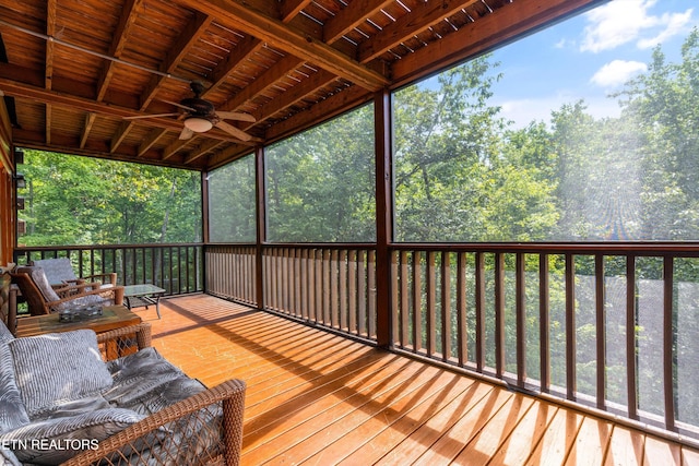 wooden deck featuring a view of trees and ceiling fan