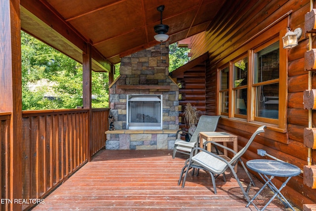 wooden deck featuring an outdoor stone fireplace