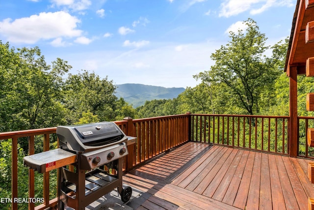 wooden deck with a forest view, a mountain view, and grilling area