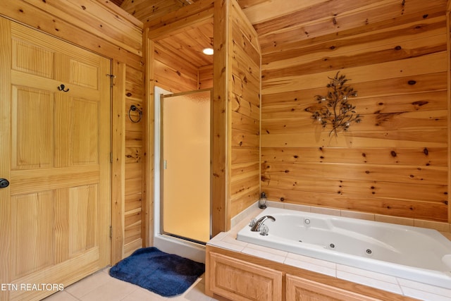 bathroom featuring tile patterned floors, wooden walls, a stall shower, and a whirlpool tub