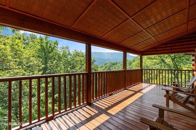 wooden terrace featuring a forest view and a mountain view