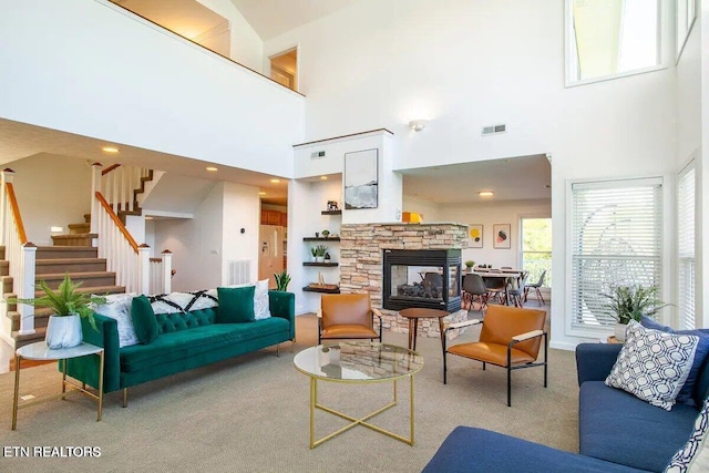 carpeted living room featuring visible vents, a fireplace, and stairway