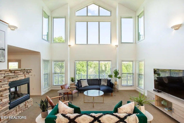 living area with a healthy amount of sunlight, a fireplace, high vaulted ceiling, and carpet floors