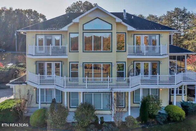 back of house with a balcony, french doors, and stucco siding