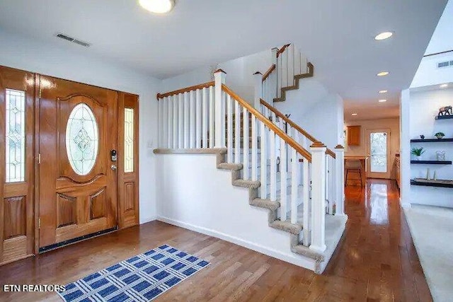 foyer with baseboards, plenty of natural light, wood finished floors, and stairs