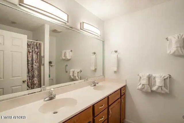 full bathroom featuring double vanity, a shower with shower curtain, and a sink