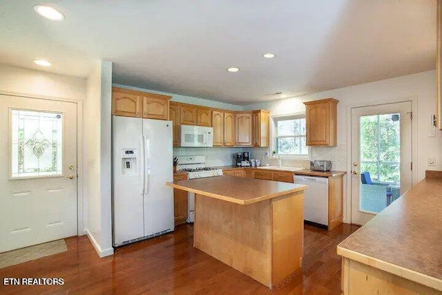 kitchen with white appliances, a kitchen island, dark wood-style flooring, and light countertops