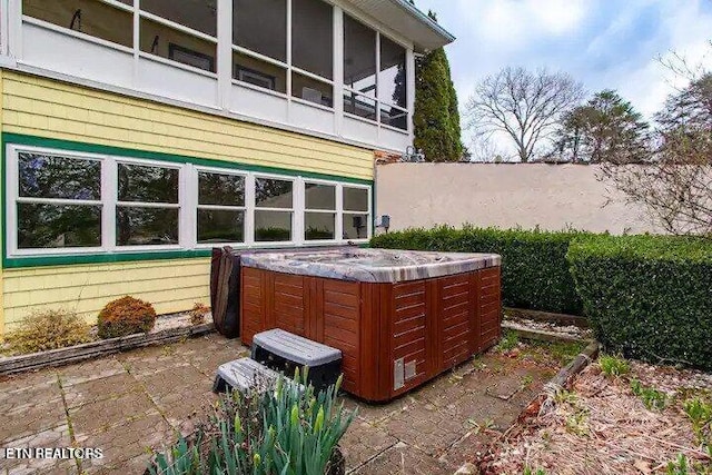 view of patio with a sunroom and a hot tub