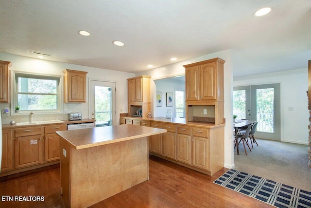 kitchen with backsplash, a kitchen island, light countertops, french doors, and a sink