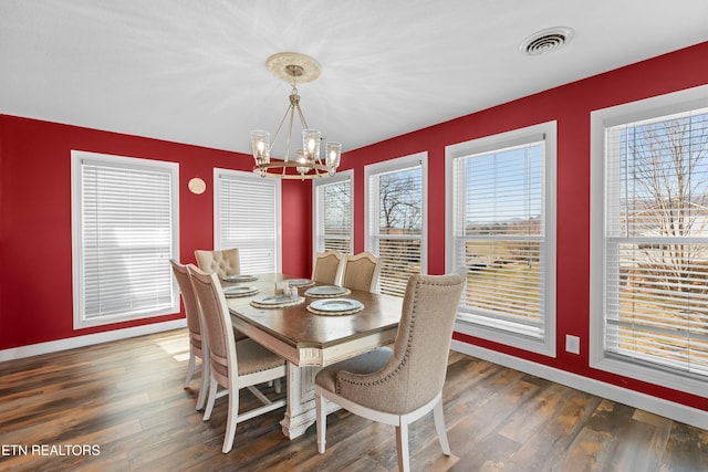 dining area with a wealth of natural light, visible vents, an inviting chandelier, and wood finished floors