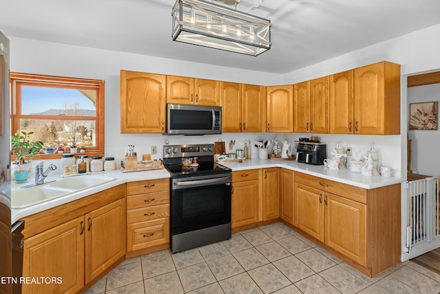 kitchen with brown cabinetry, light tile patterned flooring, a sink, stainless steel appliances, and light countertops