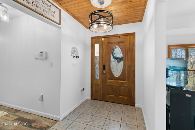 entryway with a notable chandelier, wood ceiling, baseboards, and light tile patterned floors