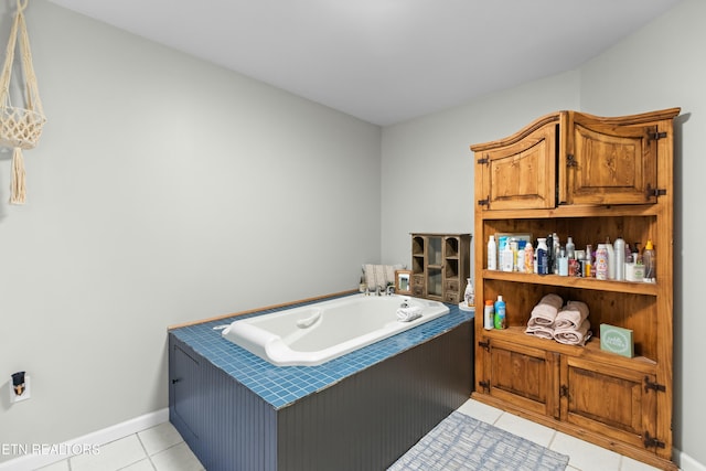 bathroom with tile patterned floors, a bath, and baseboards