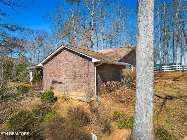 view of home's exterior featuring fence and brick siding