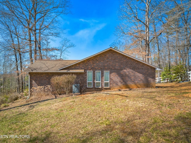 rear view of property featuring a yard and brick siding