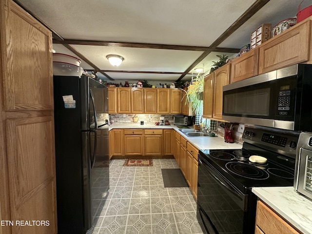 kitchen featuring tasteful backsplash, light countertops, light tile patterned floors, black appliances, and a sink