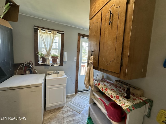 clothes washing area with cabinet space and a sink