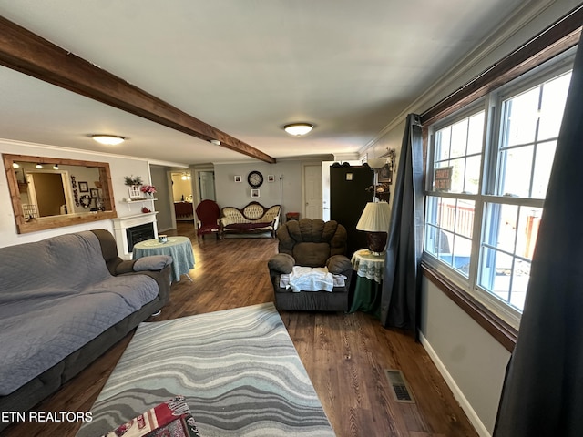 living room featuring visible vents, beam ceiling, wood finished floors, a fireplace, and crown molding