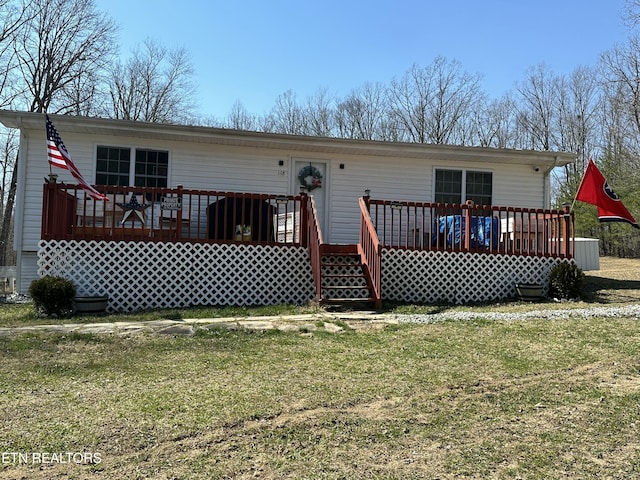 rear view of property featuring a deck and a lawn