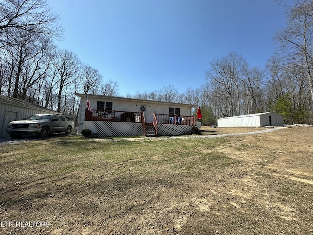 manufactured / mobile home featuring an outbuilding, a front lawn, and a wooden deck