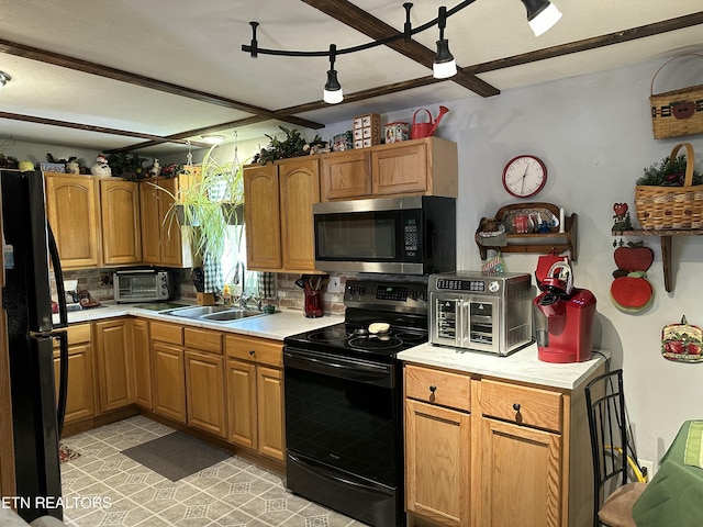 kitchen with tasteful backsplash, a toaster, light countertops, black appliances, and a sink