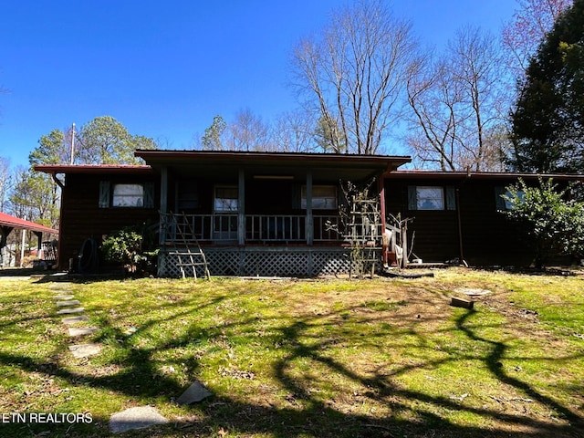 back of property with covered porch and a lawn