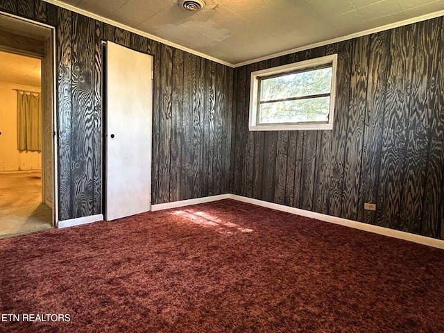 unfurnished bedroom featuring baseboards, carpet, ornamental molding, and wooden walls