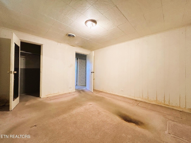 unfurnished bedroom featuring a walk in closet, a closet, visible vents, and carpet floors