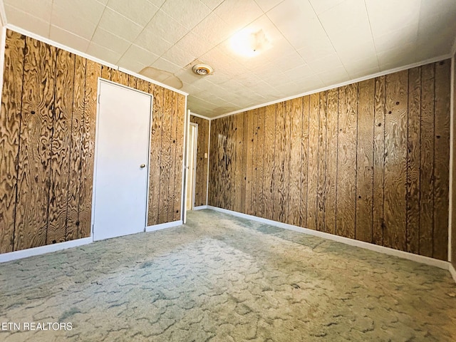 carpeted empty room with visible vents, baseboards, and wooden walls