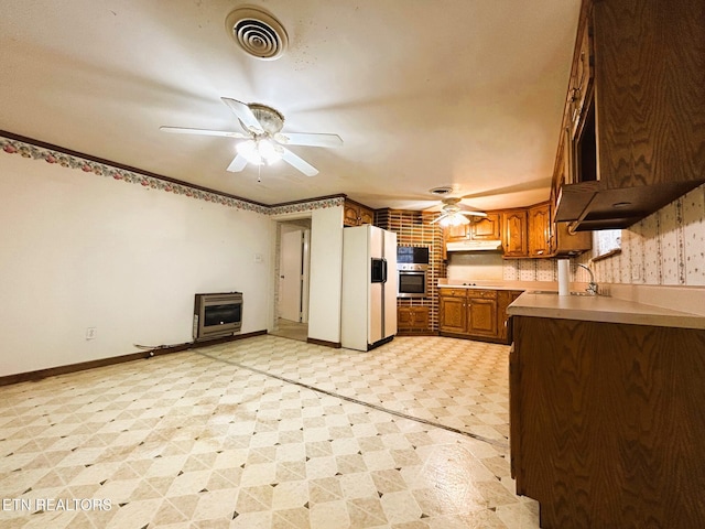 kitchen featuring visible vents, light floors, appliances with stainless steel finishes, heating unit, and a ceiling fan