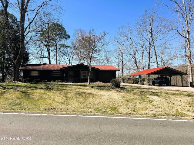 view of front of property with metal roof, a detached carport, and a front lawn