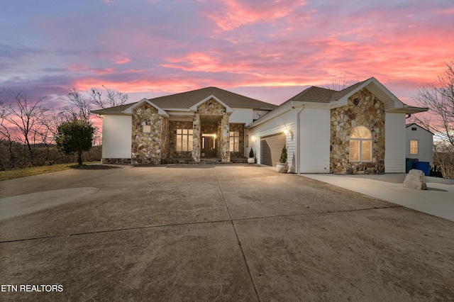 view of front of property with stone siding, an attached garage, and driveway