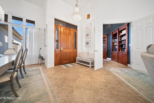 entrance foyer with light tile patterned floors, baseboards, a towering ceiling, crown molding, and a chandelier