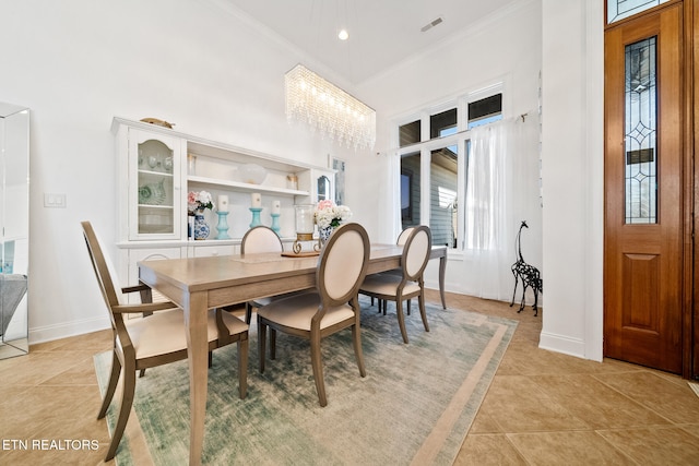 dining room featuring baseboards, a high ceiling, and ornamental molding