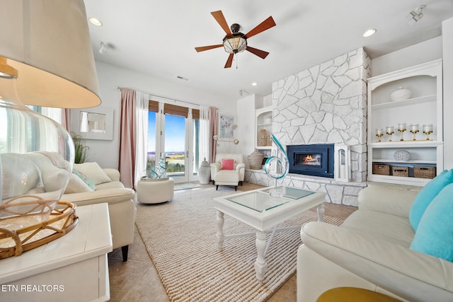 tiled living area with built in features, recessed lighting, a stone fireplace, and ceiling fan