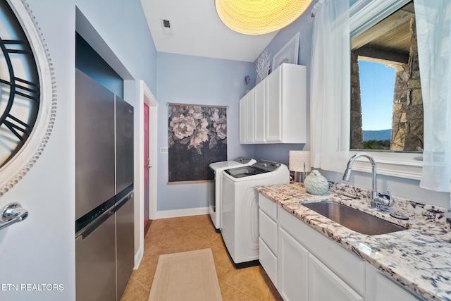 washroom featuring washing machine and clothes dryer, visible vents, light tile patterned flooring, cabinet space, and a sink