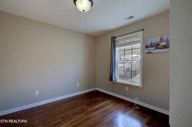 spare room featuring dark wood-type flooring, baseboards, and visible vents